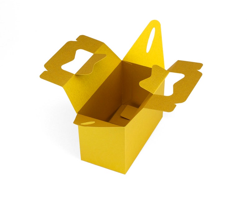May include: A gold cardboard box with two cut-out handles on the sides and one on the top. The box is open and empty.