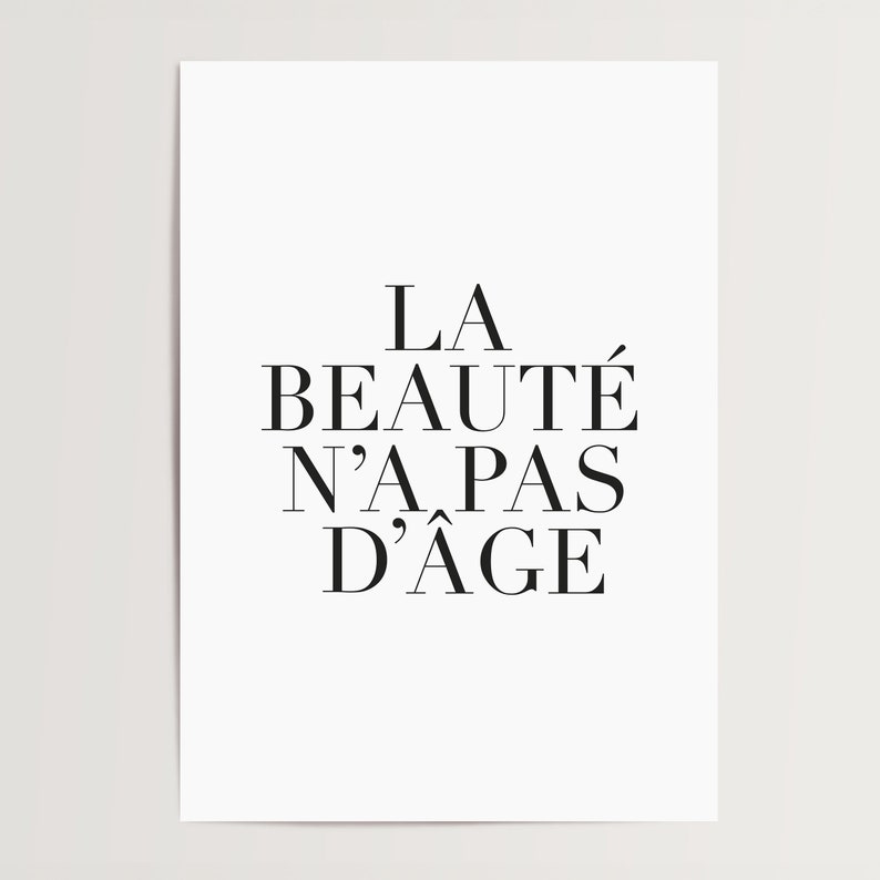 Puede incluir: Impresi&oacute;n tipogr&aacute;fica en blanco y negro con la frase francesa "La beaut&eacute; n'a pas d'&acirc;ge", que se traduce como "La belleza no tiene edad".