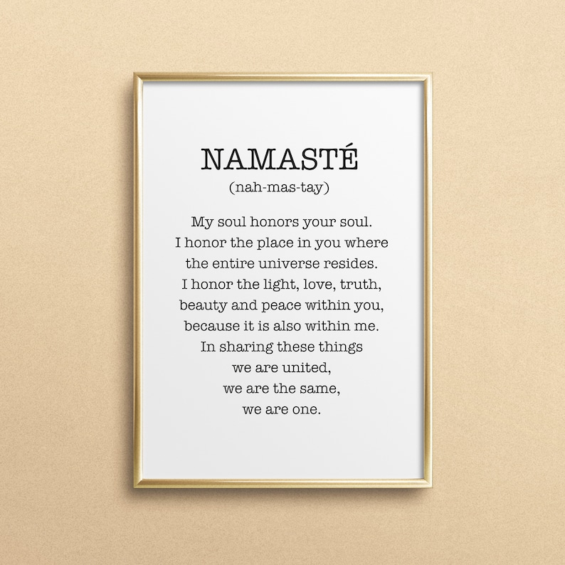 May include: A gold framed print with the word "Namaste" in black text, followed by the pronunciation in parentheses. The print includes a definition of the word, which is a Sanskrit greeting meaning "I bow to you".