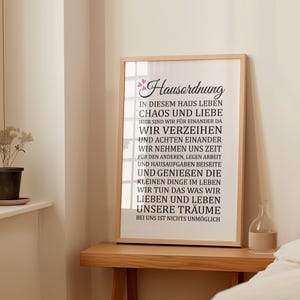 May include: A black and white printable wall art print with a quote about living in harmony with chaos and love. The quote reads "Hausordnung: In diesem Haus leben Chaos und Liebe. Hier sind wir f&uuml;r einander da. Wir verzeihen und achten einander. Wir nehmen uns Zeit f&uuml;r den anderen, legen Arbeit und Hausaufgaben beiseite und genie&szlig;en die kleinen Dinge im Leben. Wir tun das was wir lieben und leben unsere Tr&auml;ume. Bei uns ist nichts unm&ouml;glich."