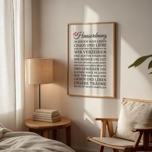 May include: A framed print with a white background and black text. The text reads "Hausordnung" and includes a list of rules for living in a home. The rules are written in German. The print is hanging on a white wall.