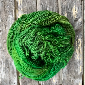 May include: A skein of green yarn with a gradient of color from a darker green to a lighter green.