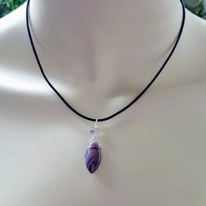 May include: A purple and white agate pendant necklace with a silver wire wrap and a black cord.