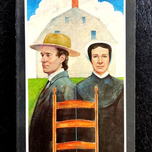May include: A rectangular book cover titled Introducing the Shakers an explanation & directory by Diana Van Kolken. The cover features an illustration of a person in a tan hat and a person in a white bonnet standing before a white building.
