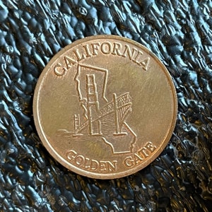 May include: A gold-colored metal token with the words "CALIFORNIA GOLDEN GATE" and an image of the Golden Gate Bridge.