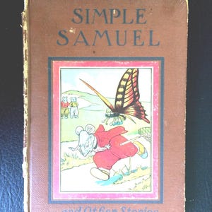 May include: A vintage children's book titled "Simple Samuel and Other Stories." The cover is brown with the title in blue. The illustration features a mouse in red clothing running from a butterfly. The book has a pink and blue border.