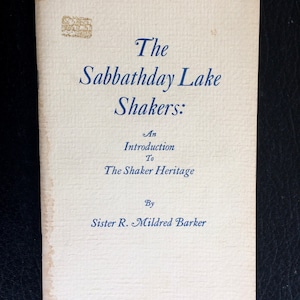 K&ouml;nnte beinhalten: Ein Vintage-Buch mit dem Titel "The Sabbathday Lake Shakers: An Introduction To The Shaker Heritage" von Sister R. Mildred Barker. Das Cover ist cremefarben mit blauem Text und einem verblassten Stempel.