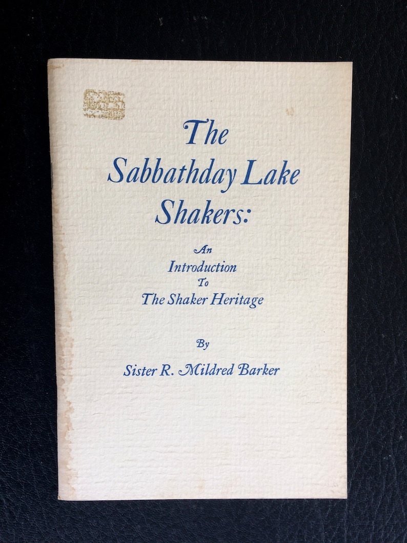 K&ouml;nnte beinhalten: Ein Vintage-Buch mit dem Titel "The Sabbathday Lake Shakers: An Introduction To The Shaker Heritage" von Sister R. Mildred Barker. Das Cover ist cremefarben mit blauem Text und einem verblassten Stempel.