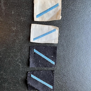 May include: Four fabric patches with blue diagonal stripes. Two patches are white and two are black.