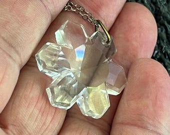 May include: A clear crystal snowflake pendant on a silver chain. The snowflake is faceted and has a delicate, intricate design.
