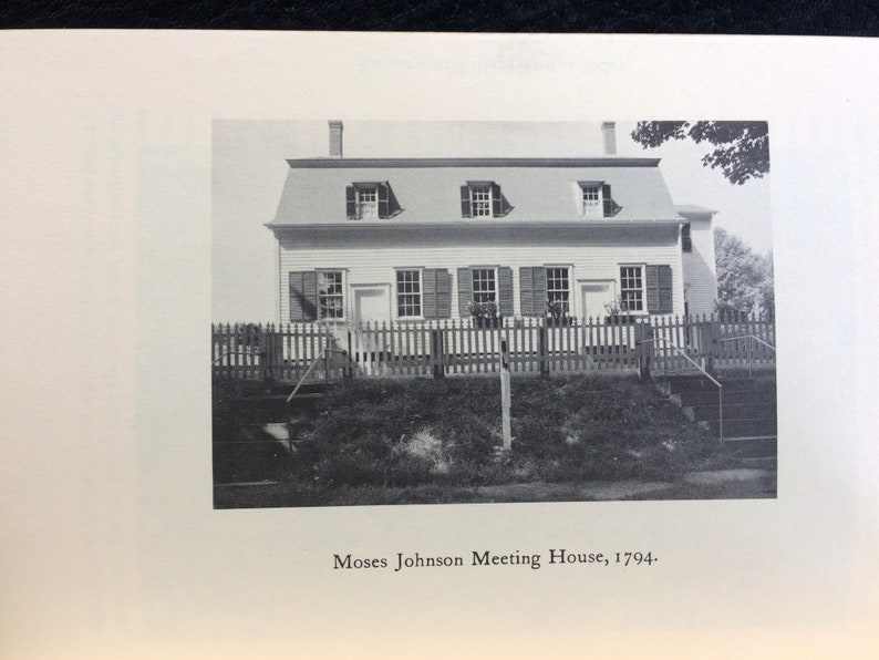 K&ouml;nnte beinhalten: Schwarz-Wei&szlig;-Fotografie des Moses Johnson Meeting House, erbaut 1794. Das Geb&auml;ude hat ein Satteldach mit drei Dachgauben und einem Schornstein. Ein Lattenzaun und Stufen f&uuml;hren zum Haus.