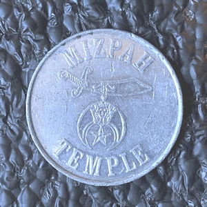 May include: A silver Mizpah Temple coin. The coin features the words "Mizpah Temple" at the top and "Temple" at the bottom. A sword and a star are in the center of the coin.