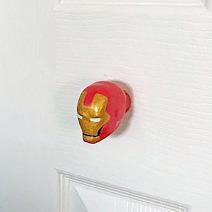 May include: Two white doors with superhero themed door knobs. The left door knob is black and shaped like Batman's head. The right door knob is red and shaped like Iron Man's head.
