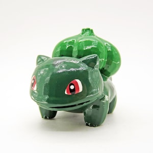 May include: Green and red plastic figurine of a cartoon character with a large green shell on its back.