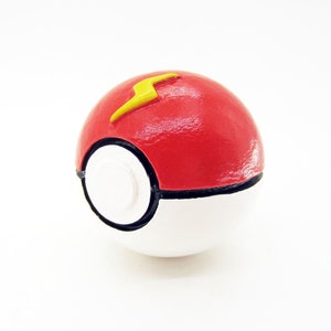 May include: A red and white Poké Ball with a yellow lightning bolt design. The Poké Ball is a popular collectible toy.