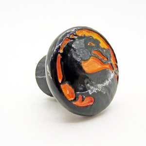 May include: Black and orange ceramic knob with a dragon design.