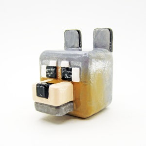 May include: A gray and brown 3D printed Minecraft wolf figurine. The wolf has black eyes and a black nose.
