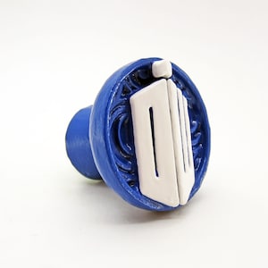 May include: Blue and white ceramic knob featuring a TARDIS design. The knob is round and has a raised design of the TARDIS, a time-traveling spaceship from the Doctor Who television series.