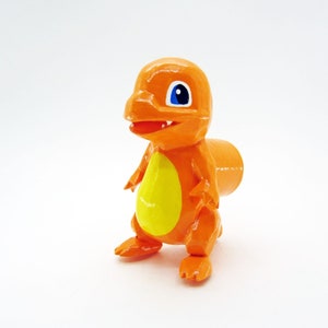 May include: Orange and yellow cartoon character figurine with blue eyes. The figurine is standing on a white surface.