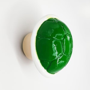 May include: Green and white plastic cabinet knob shaped like a turtle shell.