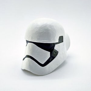 May include: A white plastic Stormtrooper helmet with black details. The helmet is a popular collectible for Star Wars fans.