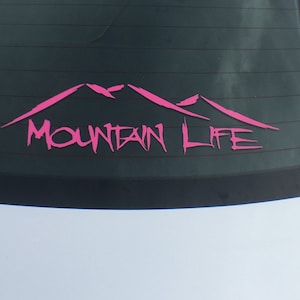 May include: Pink vinyl decal with a mountain range silhouette and the words "Mountain Life" in a stylized font.