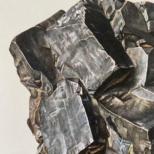 May include: A close-up of a dark gray, metallic mineral with a rough, textured surface. The mineral has a crystalline structure and appears to be made up of several smaller crystals.