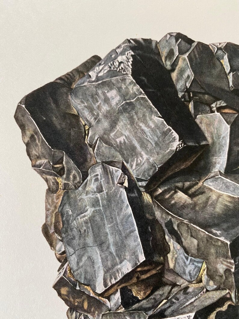 May include: A close-up of a dark gray, metallic mineral with a rough, textured surface. The mineral has a crystalline structure and appears to be made up of several smaller crystals.