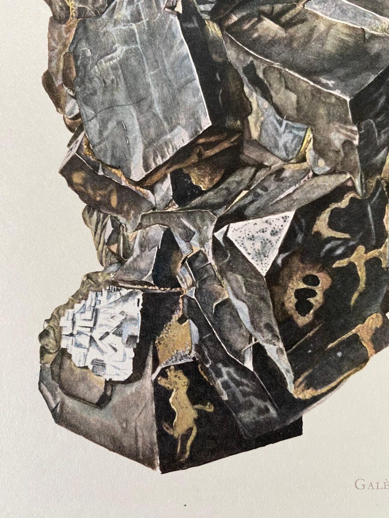 May include: A close-up of a dark gray and black mineral specimen with a rough, textured surface. The mineral has a crystalline structure and appears to be a type of galena.