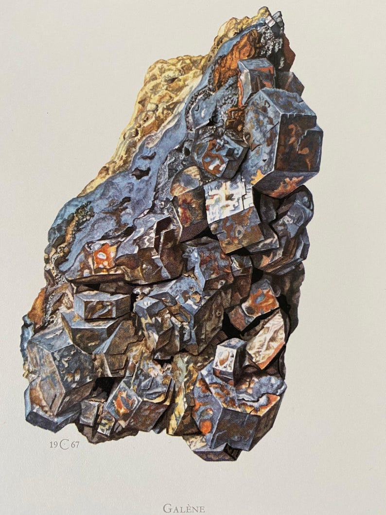 Może przedstawiać: Zbliżenie na duży, szary, sześcienny okaz minerału galeny. Minerał ma metaliczny połysk i jest otoczony macierzą innych minerał&oacute;w, w tym ż&oacute;łtych i pomarańczowych odcieni.