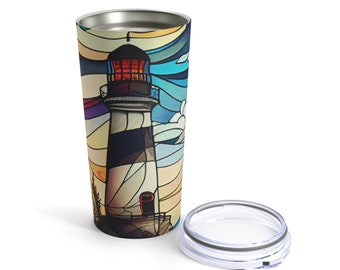 May include: A stainless steel tumbler with a colorful stained glass design of a lighthouse against a blue sky. The tumbler has a lid.