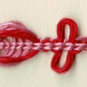 May include: Close-up of a decorative trim featuring a repeating pattern of red and pink embroidered shapes. The trim has a chain stitch in light pink, with red loops and pink floral-like designs. The background is a light beige color.