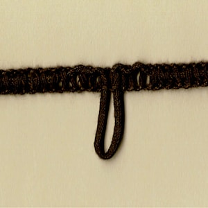 May include: Brown braided cord with a loop at the end. The cord is made of a woven material and has a textured surface.