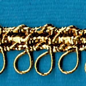 May include: Gold trim with a decorative design and a row of metal loops.