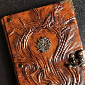 It features a handmade embossed real leather journal with an esoteric symbol of All-Seeing Eye charm on its cover. Journal has a swing hook clasp closure.