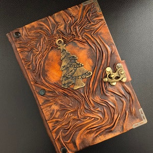 Handmade leather Christmas journal with wrinkled texture, featuring Christmas tree charm on the flat upper middle of the cover and a swing hook clasp closure on the right side. Perfect handmade Xmas holiday gift.