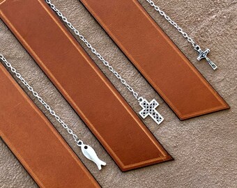 May include: Three brown leather bookmarks with silver chains and charms. The charms are a cross, a cross, and a fish.