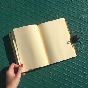 Open handmade leather journal showing blank pages for writing or sketching.