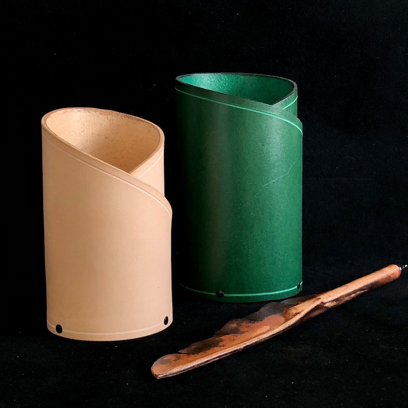 K&ouml;nnte beinhalten: Zwei Bleistifthalter aus Leder, einer beige und einer gr&uuml;n, mit einem Holzstift.