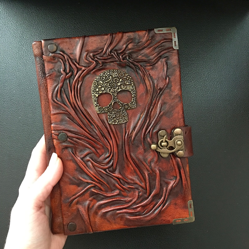 It features an embossed real leather cover with an old school style skull on it. Leather journal has swing hook clasp closure.