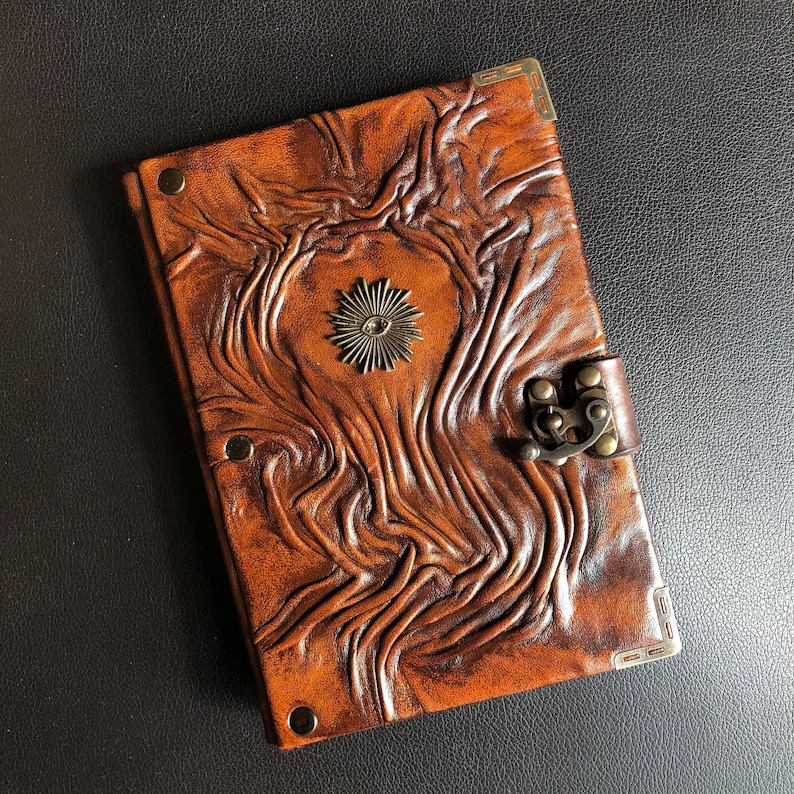 It features a handmade embossed real leather journal with an esoteric symbol of All-Seeing Eye charm on its cover. Journal has a swing hook clasp closure.