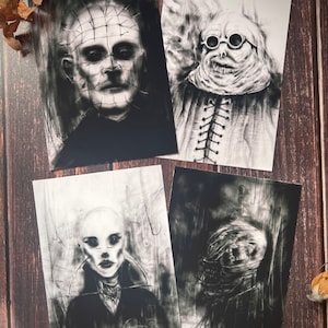 May include: Four black and white horror art prints featuring portraits of eerie characters. The prints showcase detailed charcoal-style illustrations with a dark, gothic aesthetic. The subjects include a figure with pins, a figure with goggles, and two other unsettling portraits.
