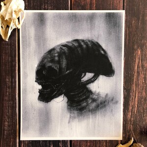 May include: A black and white drawing of an alien creature with a large head and sharp teeth. The creature is depicted in a shadowy, atmospheric style.
