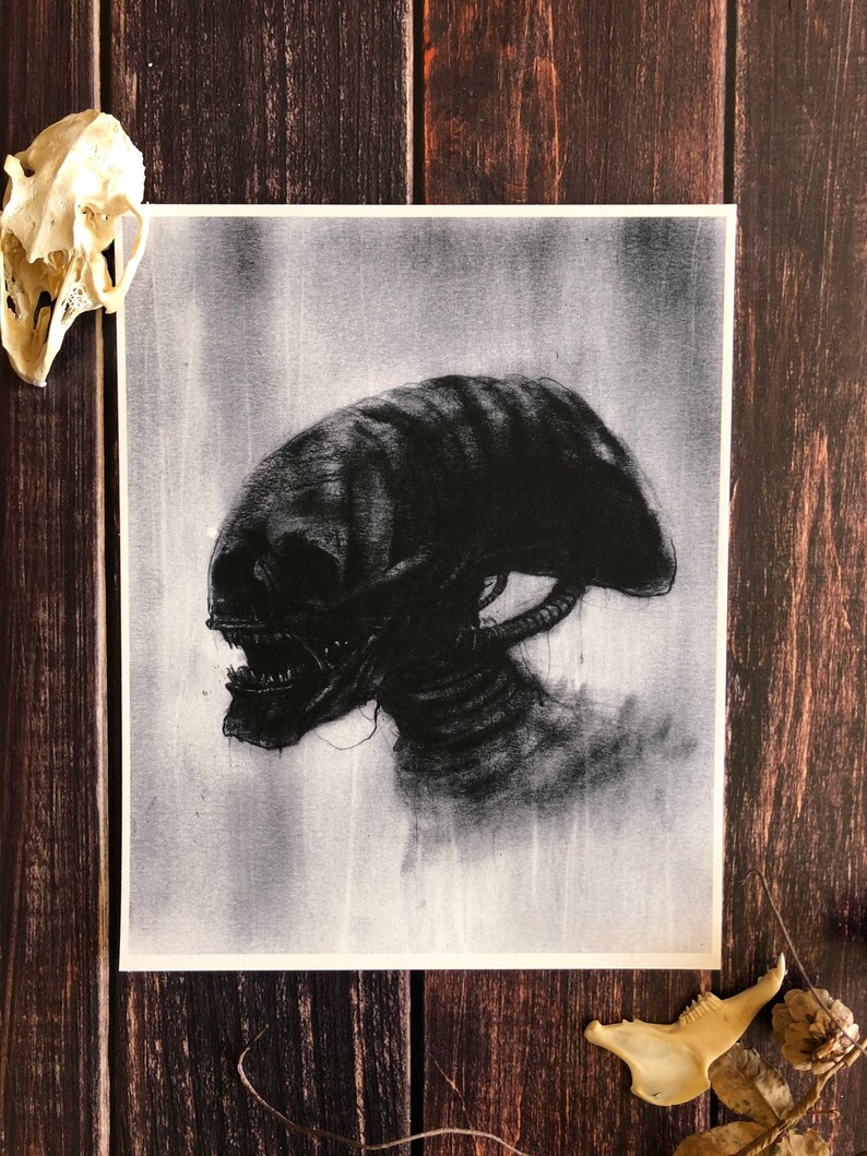 May include: A black and white drawing of an alien creature with a large head and sharp teeth. The creature is depicted in a shadowy, atmospheric style.