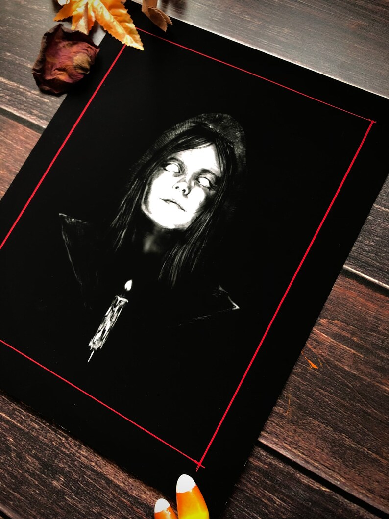 Puede incluir: Ilustraci&oacute;n en blanco y negro de una persona con ojos brillantes y una vela. La obra de arte est&aacute; enmarcada con un borde rojo y sobre un fondo oscuro. La persona lleva una prenda con capucha.