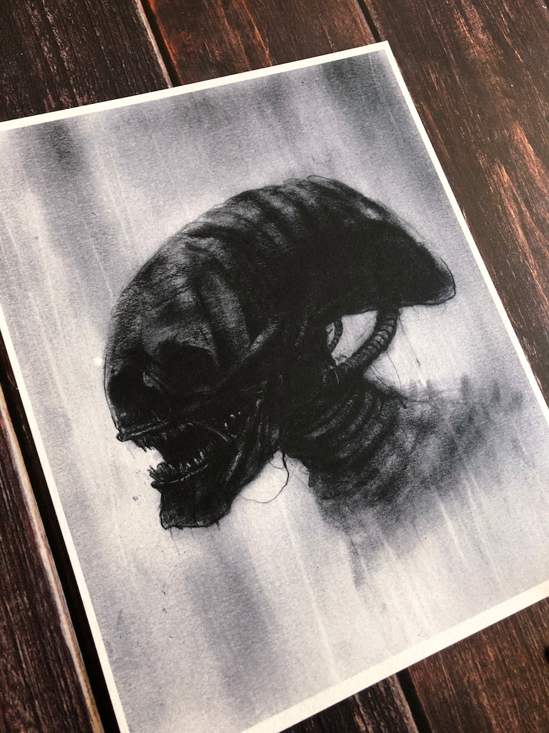 May include: A black and white drawing of an alien creature with a large head and sharp teeth. The creature is depicted in profile, with its head turned to the side. The drawing is done in a realistic style, with detailed shading and texture.