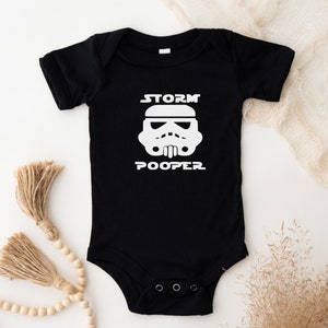 baby star wars onesie. Black onesie with a  storm trooper head and the words storm pooper applied in white vinyl on the front.