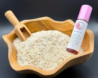 May include: A wooden bowl filled with white bath salts and a small pink bottle labeled "Moldavite" with a description of its benefits.