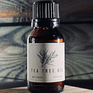 May include: A small brown glass bottle with a black lid, containing tea tree oil. The bottle has a white label with the text "TEA TREE OIL" and "BATCH#001 0.5 FL OZ".