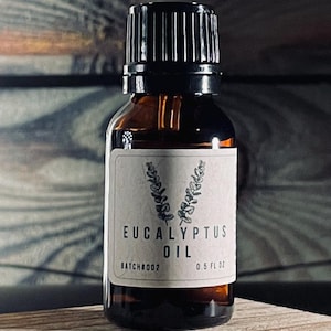 May include: A small amber glass bottle with a black cap, containing eucalyptus oil. The bottle has a white label with the text "Eucalyptus Oil" and "Batch#002 0.5 fl oz".